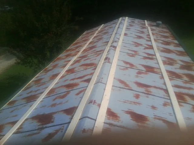 Rusted metal roof panels with new wood purlins before replacement — Storm Damage Roof Repair in Pilot Mound by Roofing Brothers
