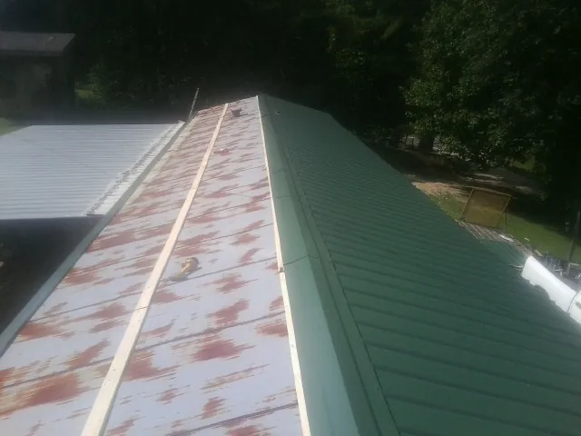 Old rusted panels beside newly installed green metal roofing — Wind Damage Roof Repair by Roofing Brothers in Pilot Mound
