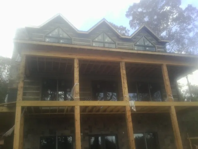 Dormers and porch framing on a large log home under construction — Roof Coating work by our crew in Pilot Mound