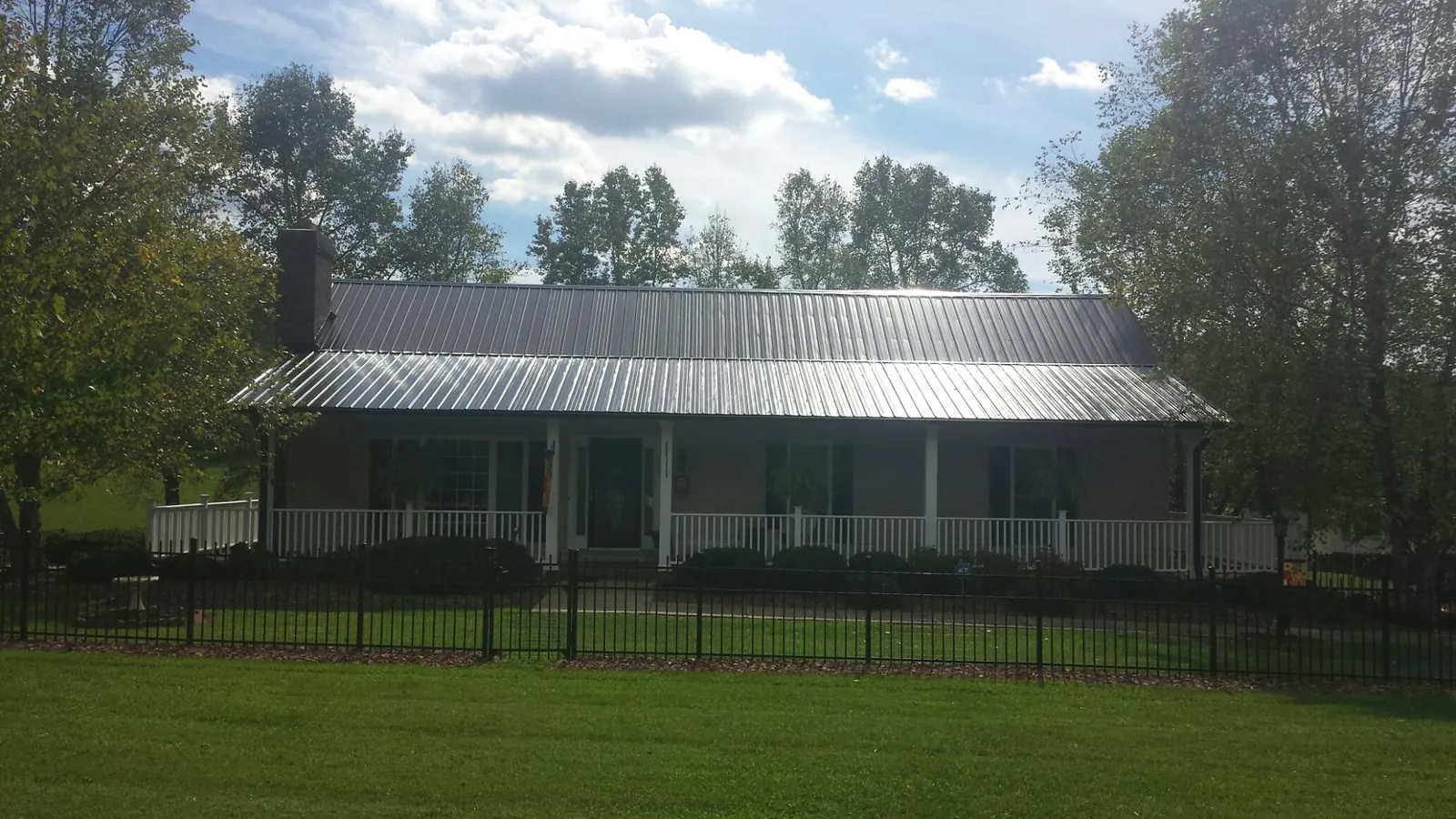 Gray metal roof on a brick ranch with a full width front porch — Gutter Guard Installation work by our crew in Pilot Mound