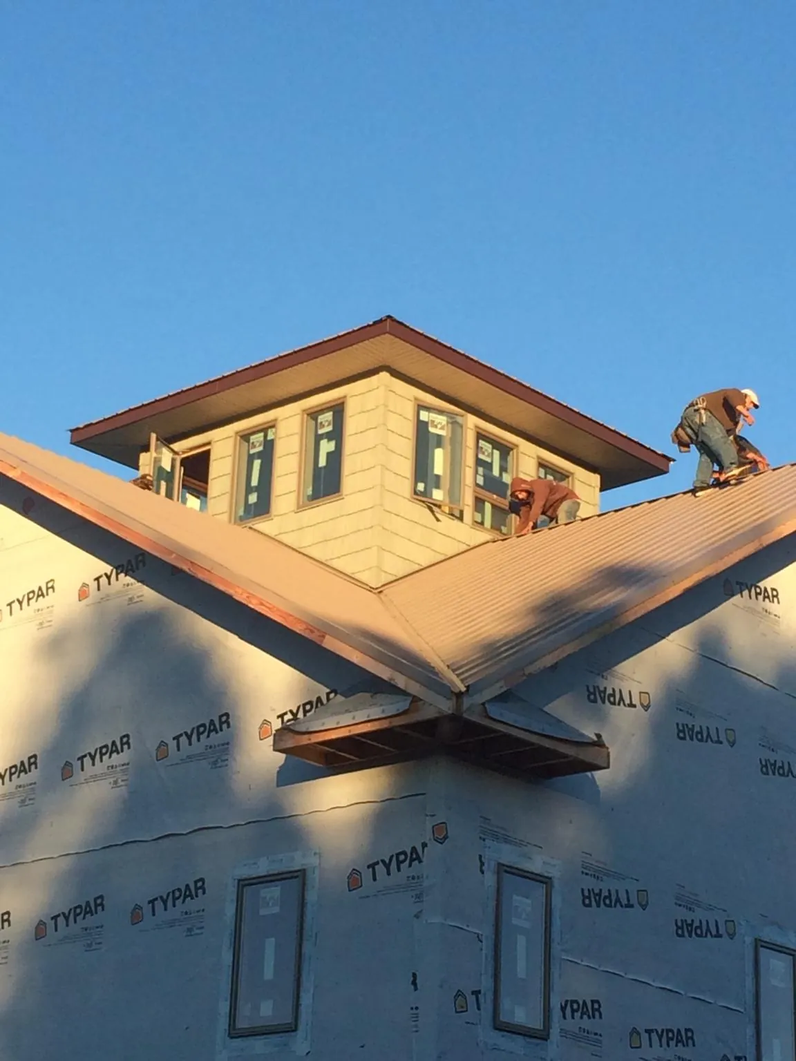 Roofers working around a rooftop cupola on a new metal roof at sunset — Roof Waterproofing in Pilot Mound by Roofing Brothers
